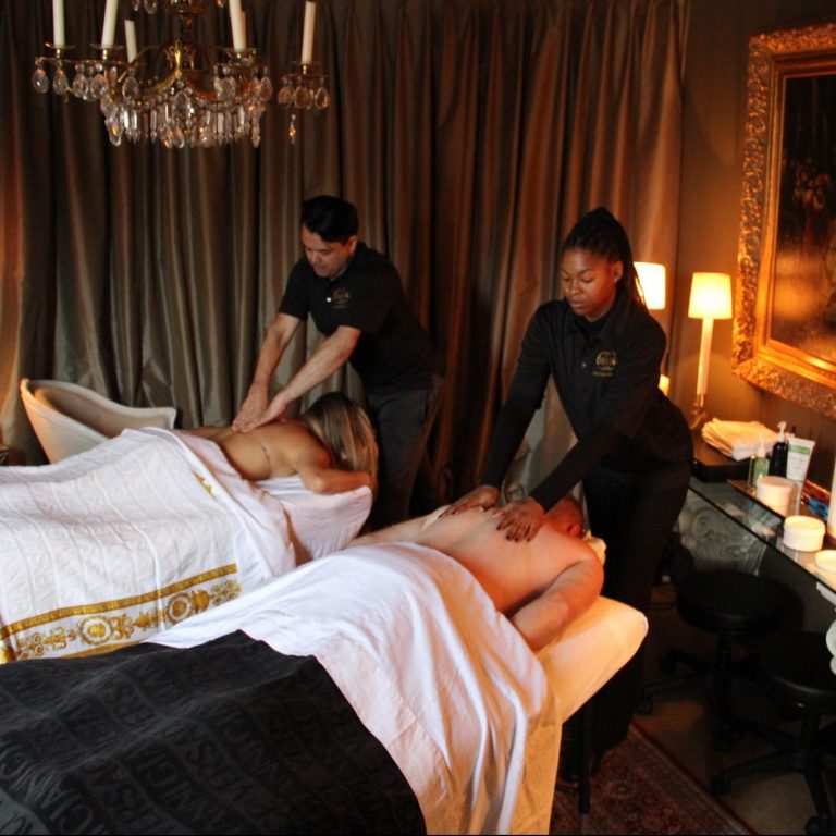 Couple experiencing romantic, relaxing couples massage from two therapists.