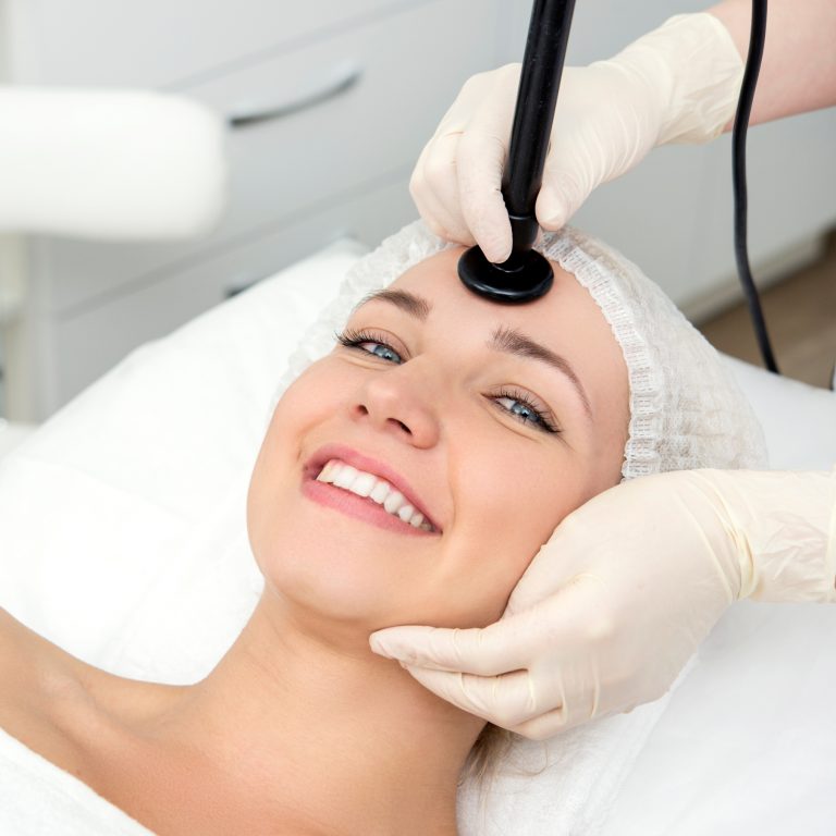Woman smiling as she receives anti-aging treatment from a medical specialist.