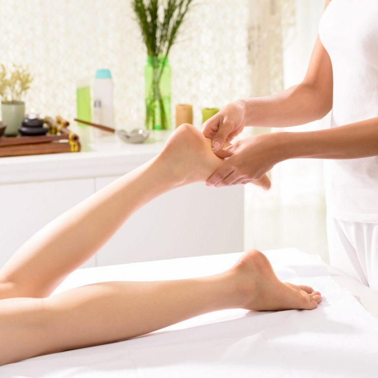 A therapist applying pressure to specific points on a woman's foot.